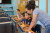 A young woman looks over the shoulder of one of four young boys working on computers.